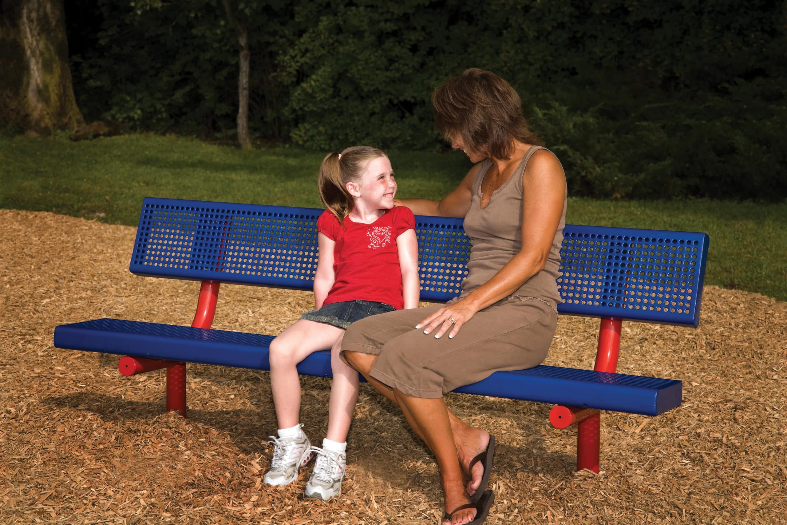 Woman and little girl sitting on a blue and red park bench